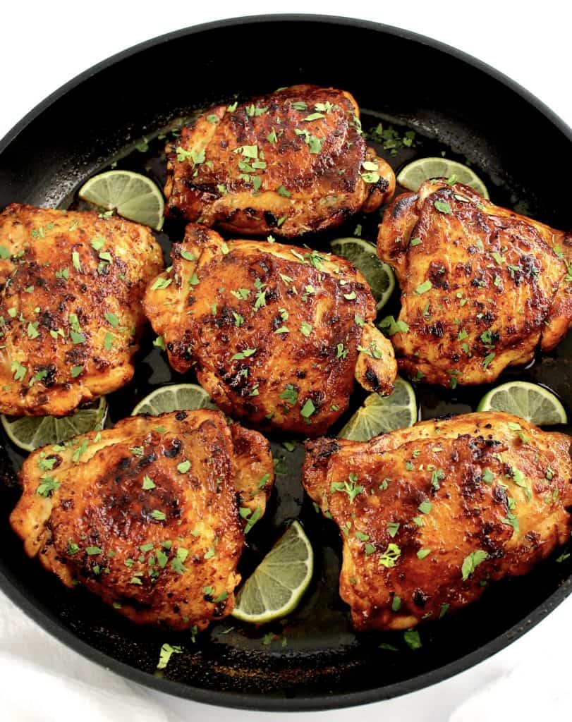 Paprika Chicken Thighs in skillet with small limes half slices