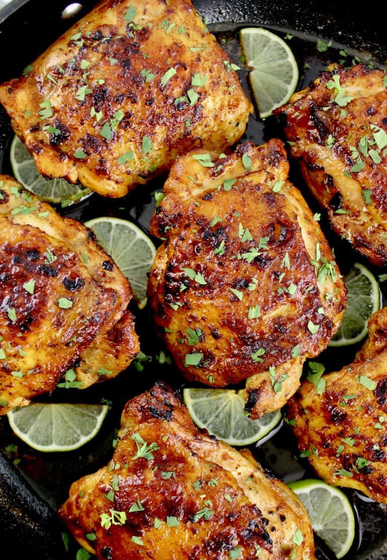 Paprika Chicken Thighs in skillet with lime slices and chopped cilantro