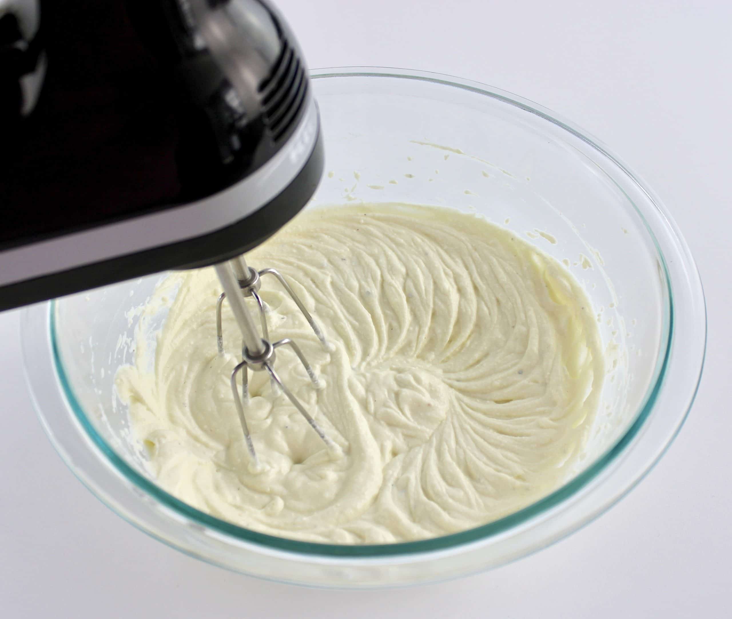 ricotta being whipped with hand mixer in glass bowl