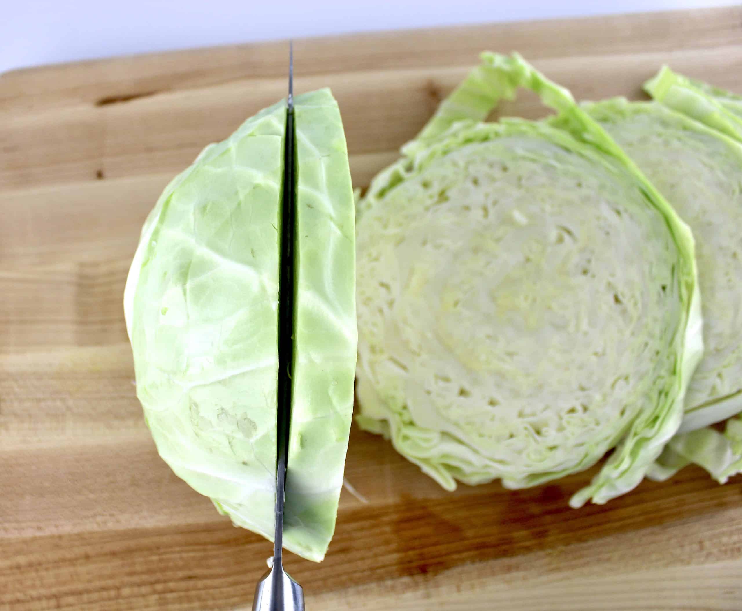 knife cutting a head of cabbage on cutting board