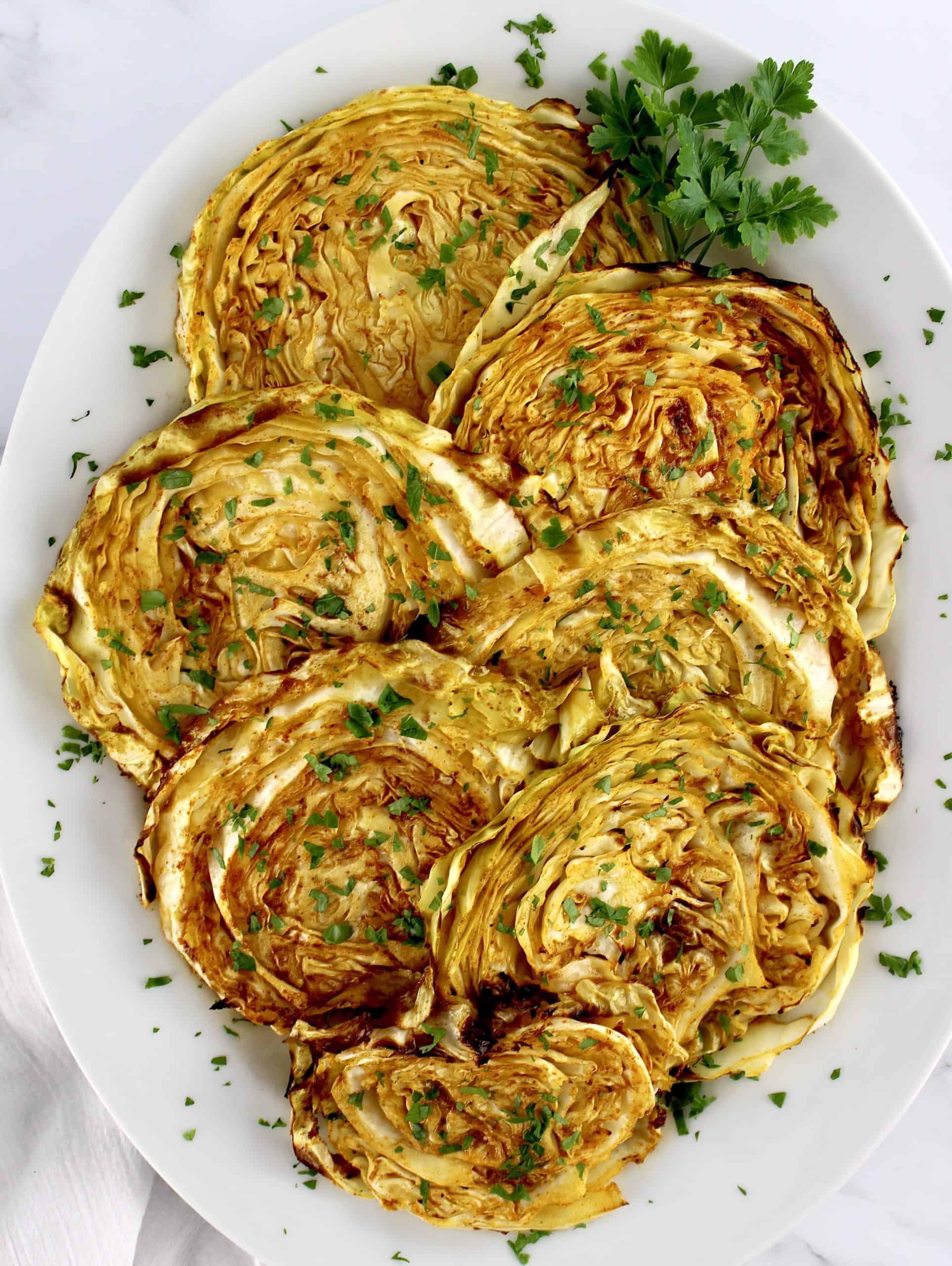 7 Roasted Cabbage Steaks on white plate with parsley garnish