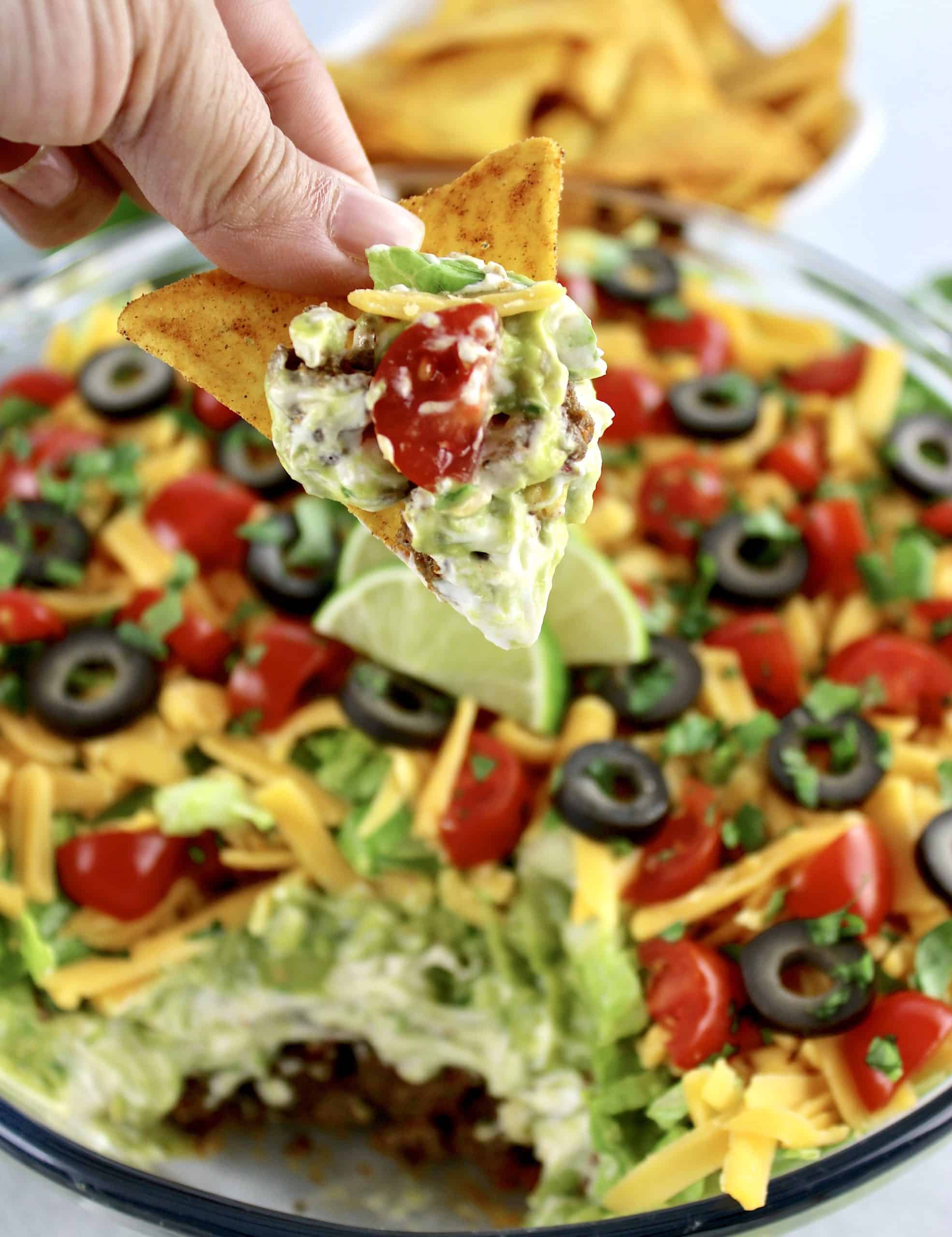 layered taco dip with tortilla chip dipped in