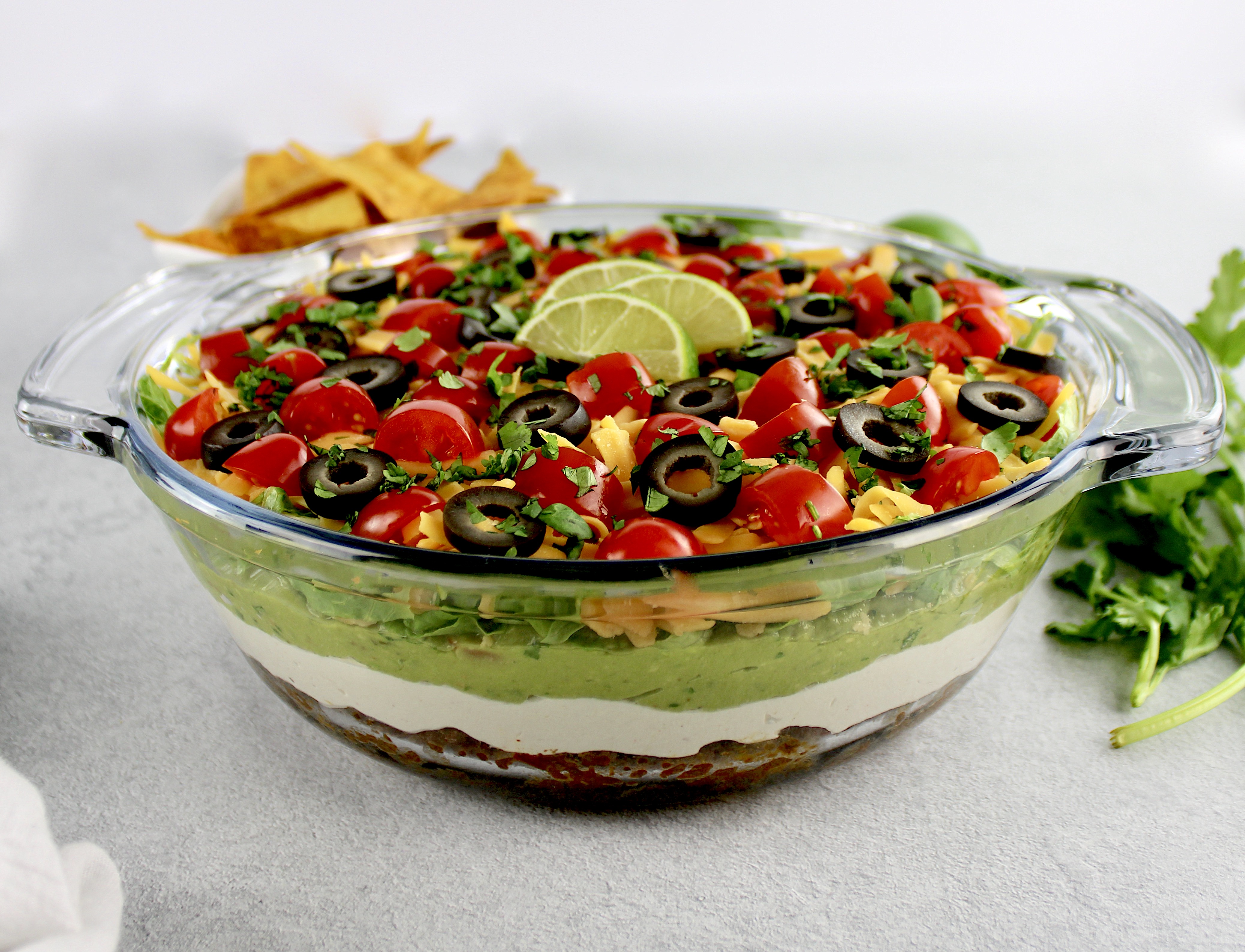 side view of layered taco dip in glass bowl