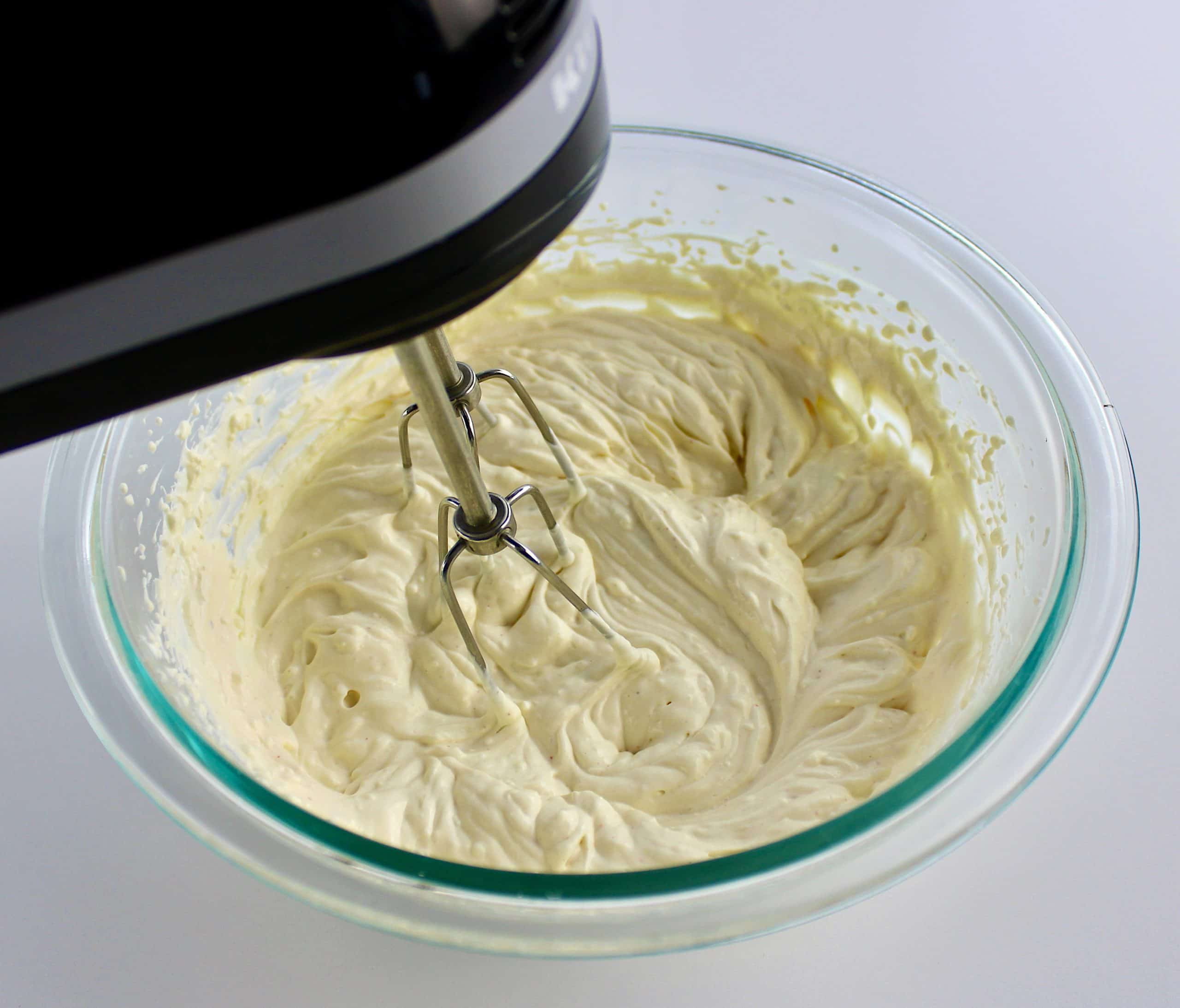 sour cream cream cheese and chipotle being mixed with hand mixer inn glass bowl