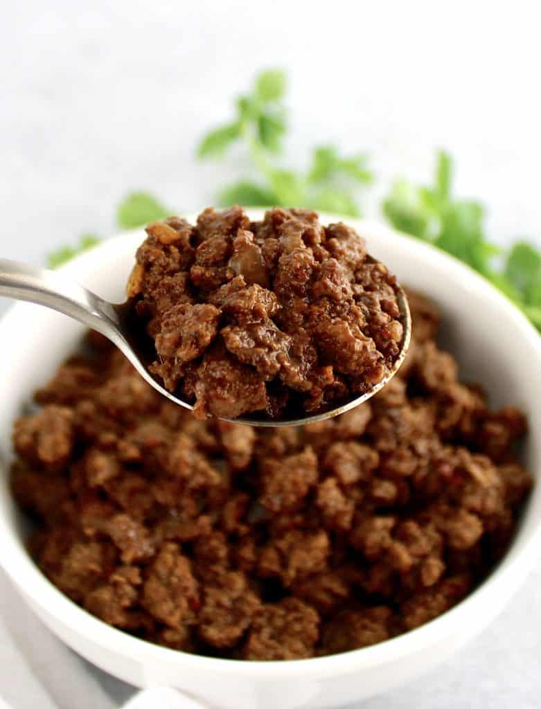 taco meat inn white bowl with spoon holding up some