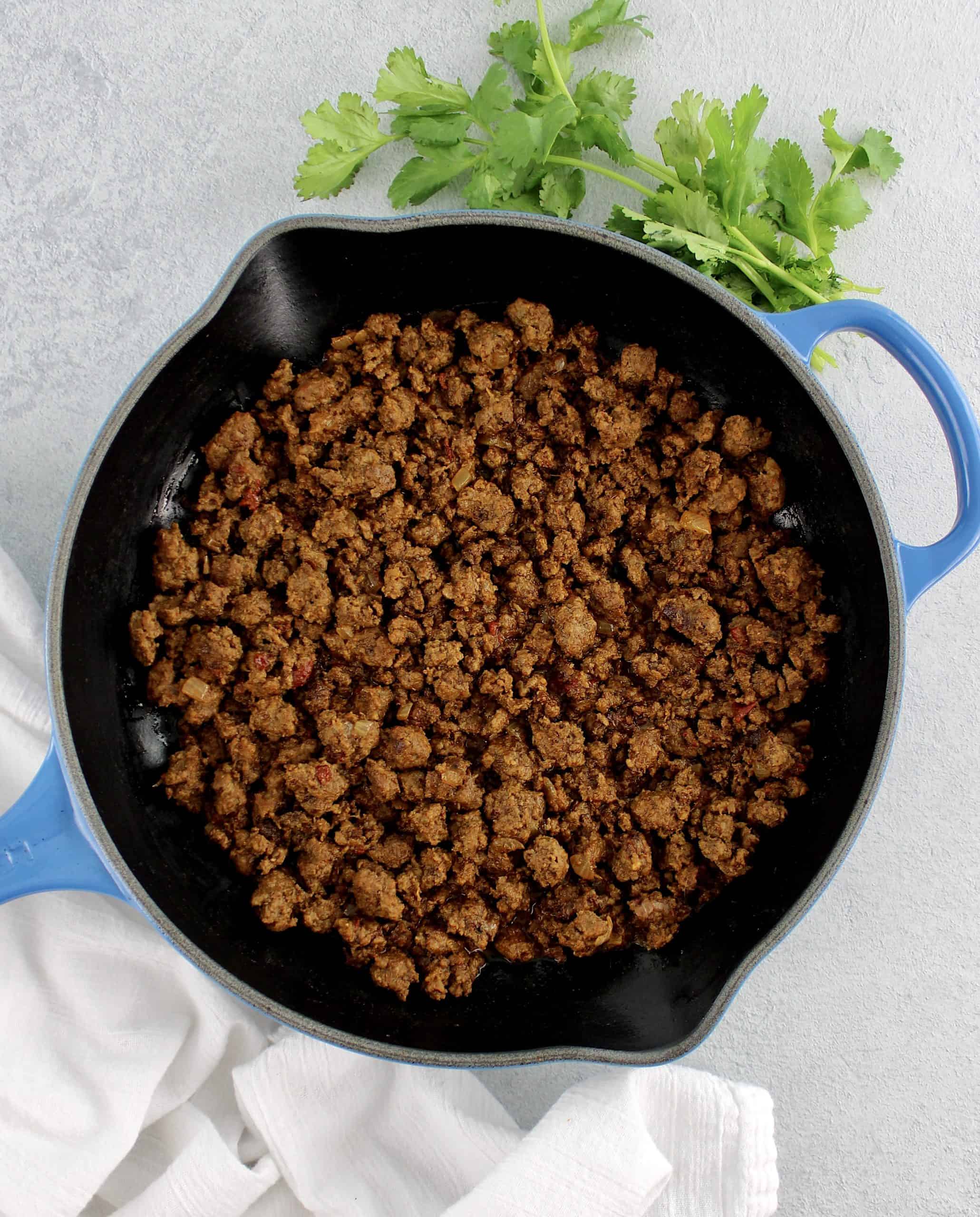 overhead view of Easy Taco Meat in cast iron skillet with cilantro on side