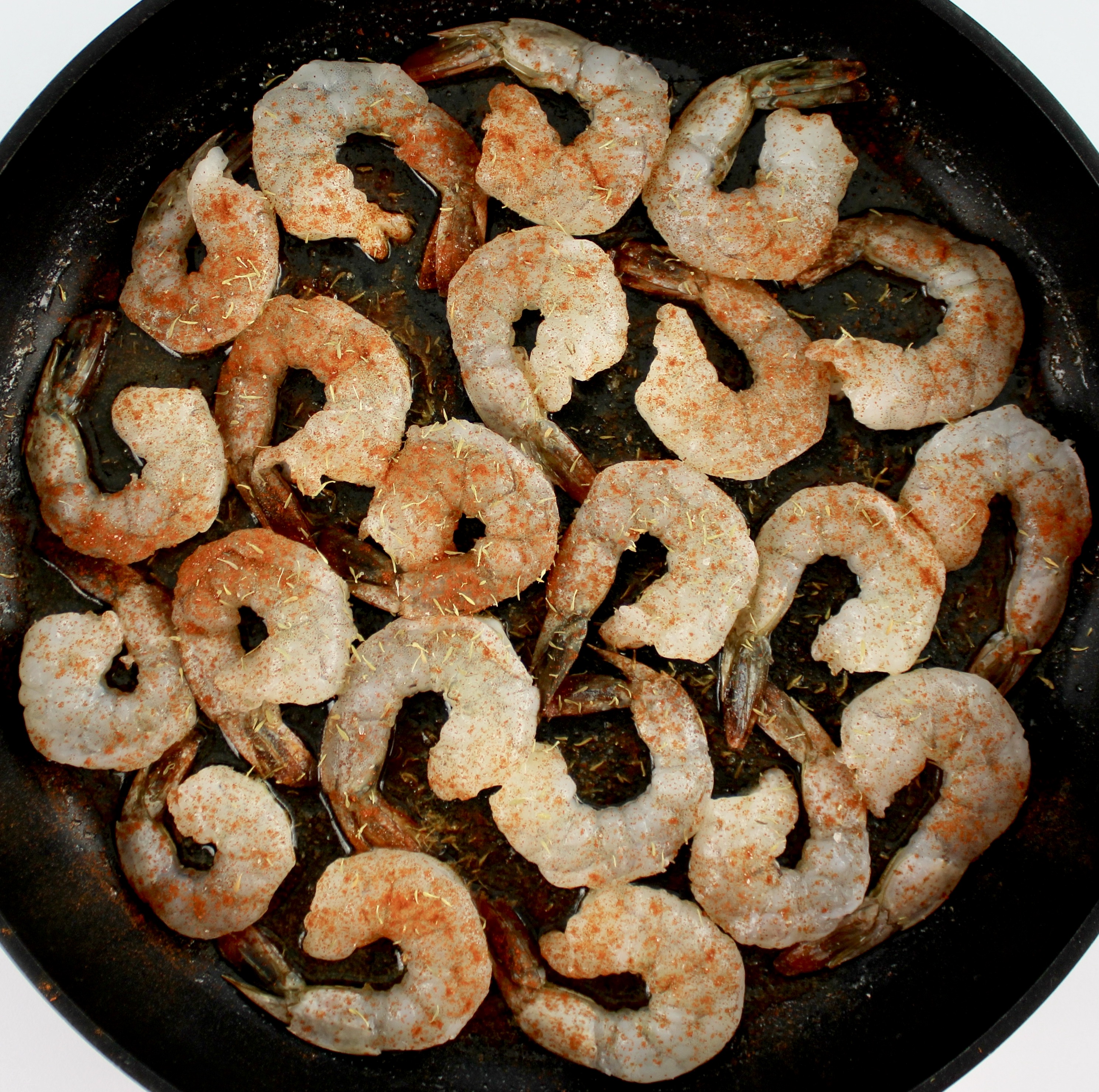 raw shrimp with spices on top in skillet