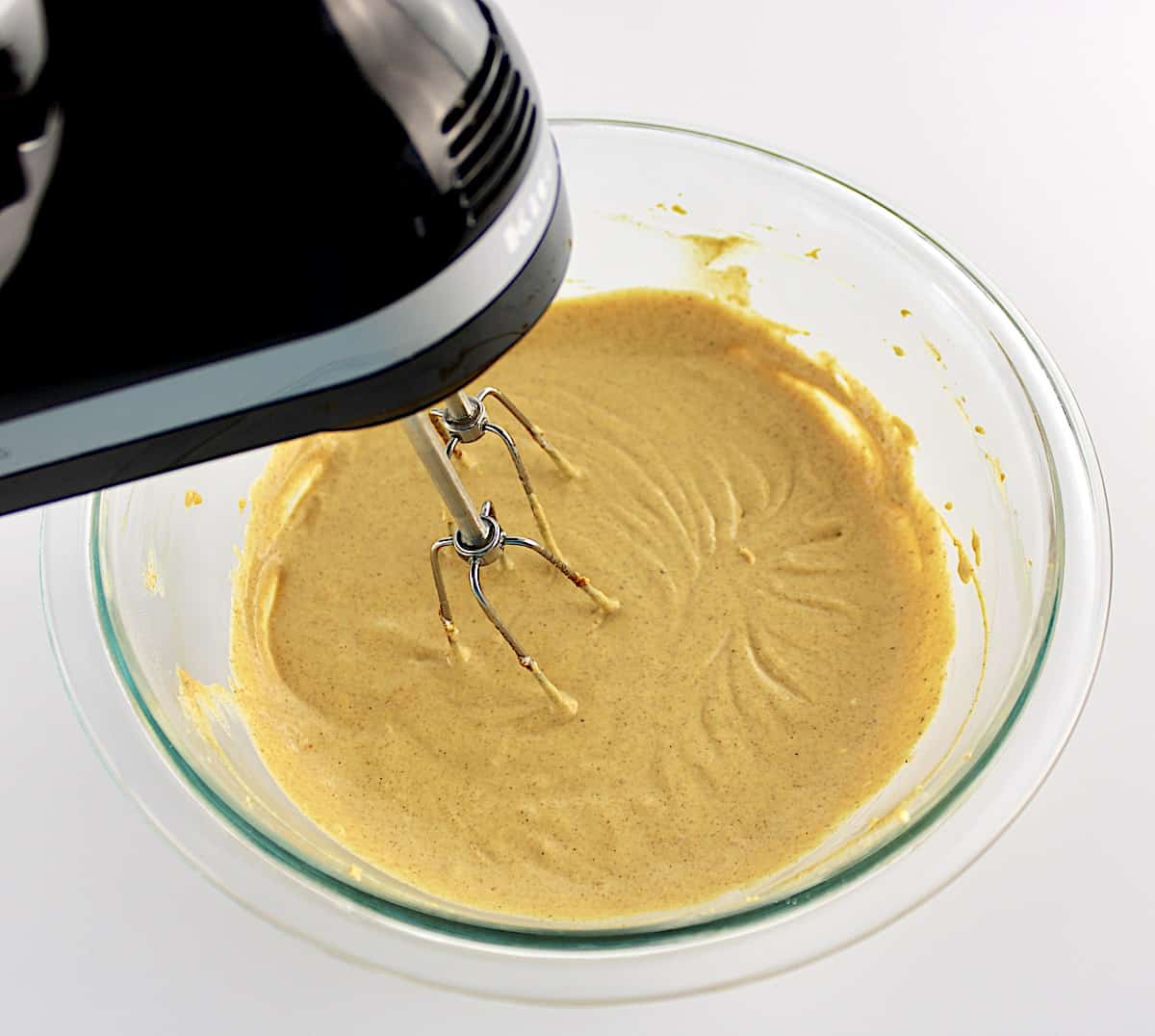 Keto Pumpkin Cheesecake Bars batter being mixed with hand mixer in glass bowl