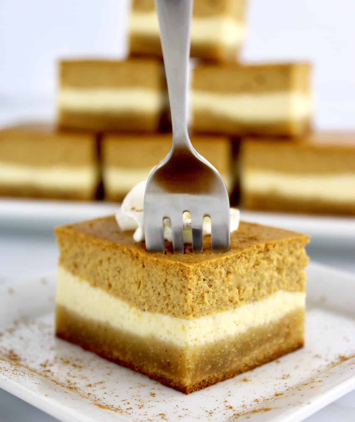 closeup of Keto Pumpkin Cheesecake Bar on white plate with fork in the top