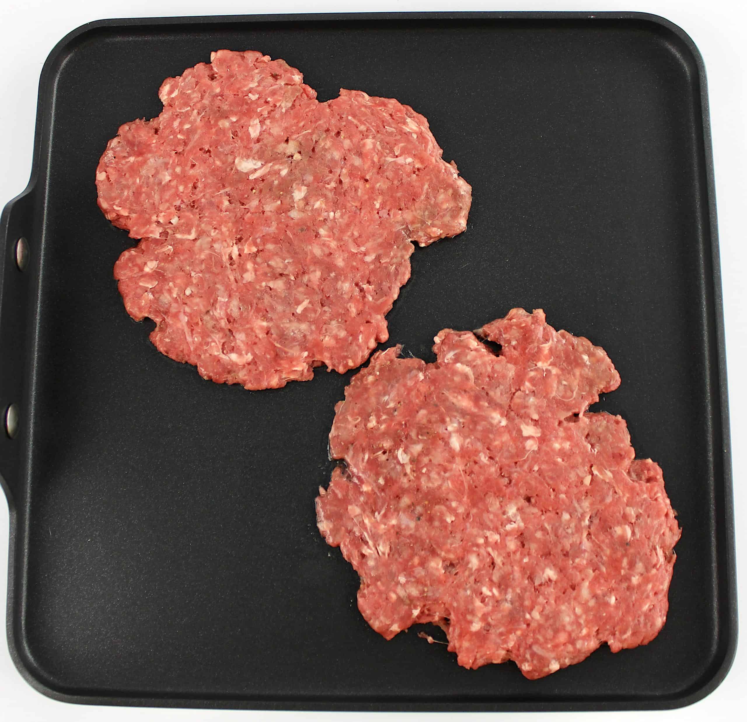 2 smash burgers raw on griddle