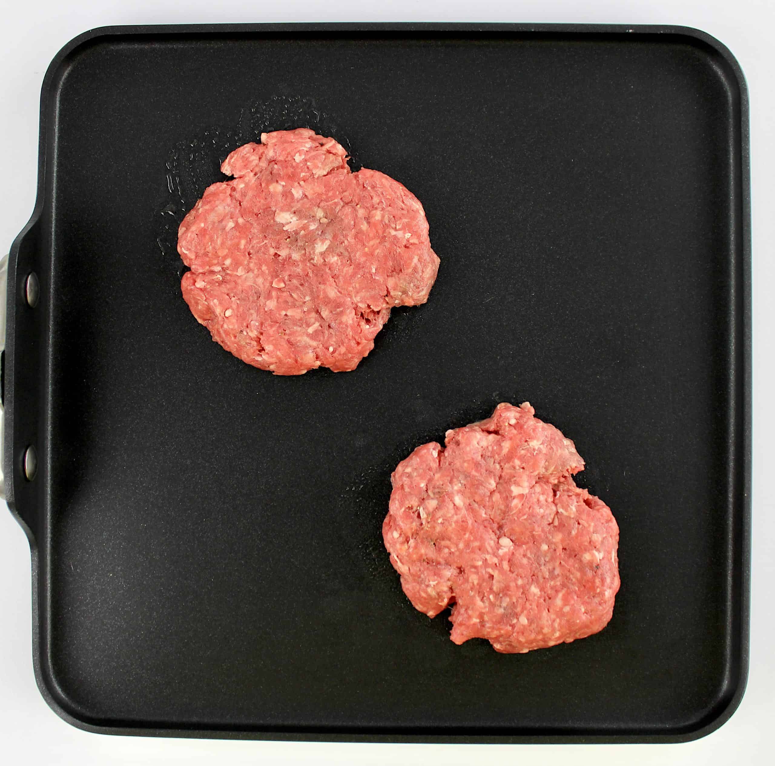 2 raw burger patties on griddle