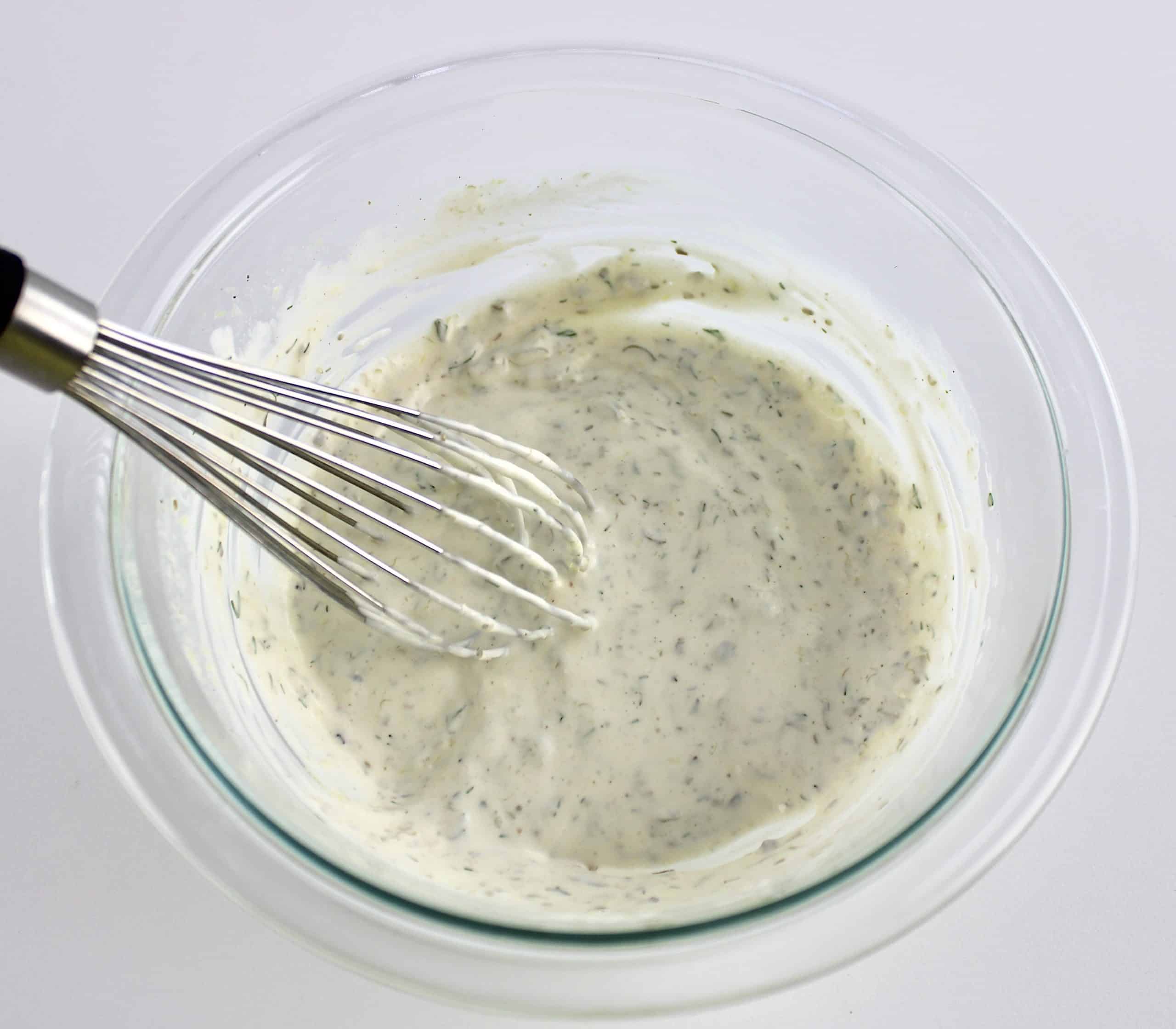 creamy dill sauce in glass bowl with whisk