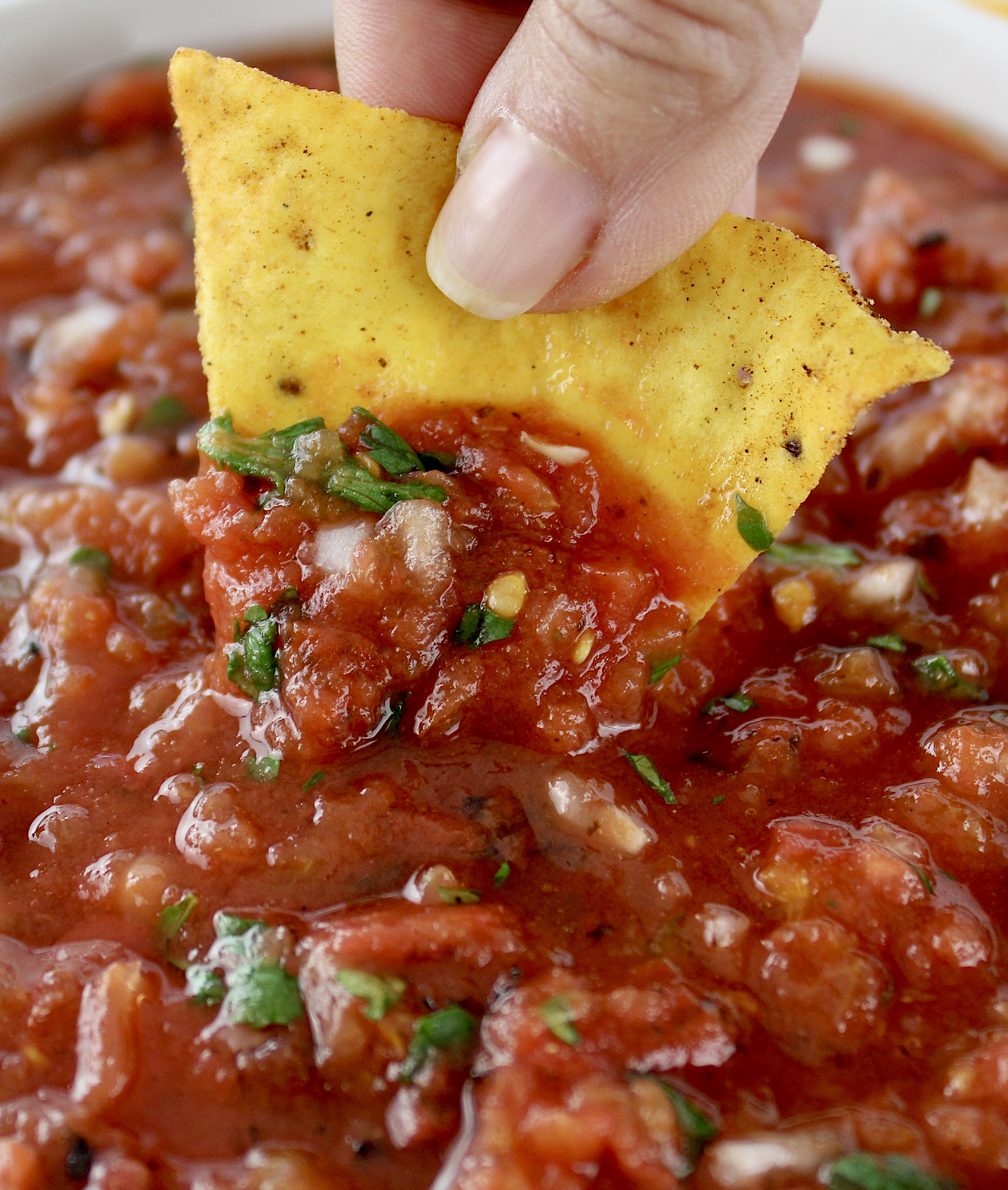 closeup of tortilla chip being dipped into salsa