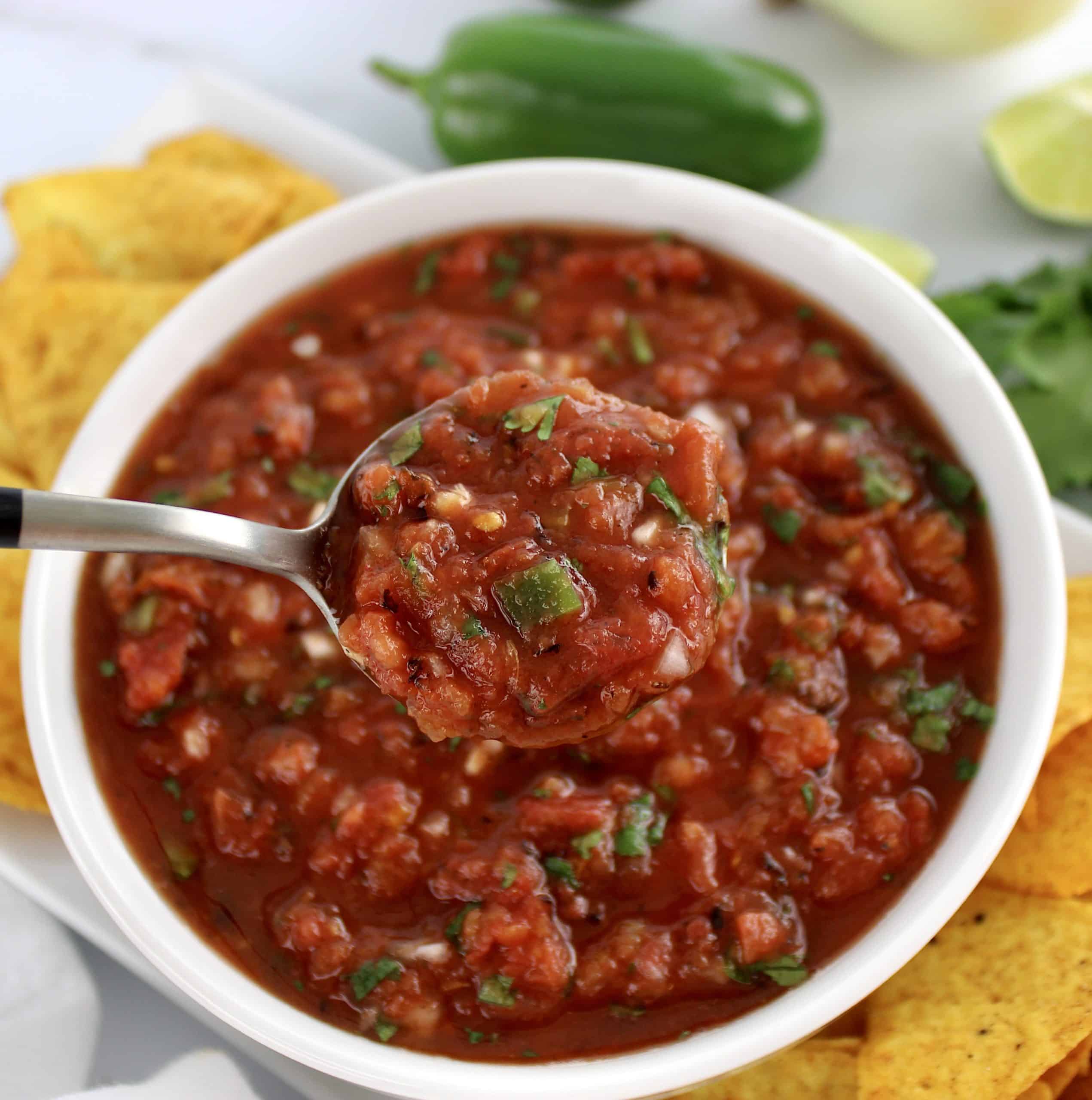 salsa in white bowl with spoon holding up some