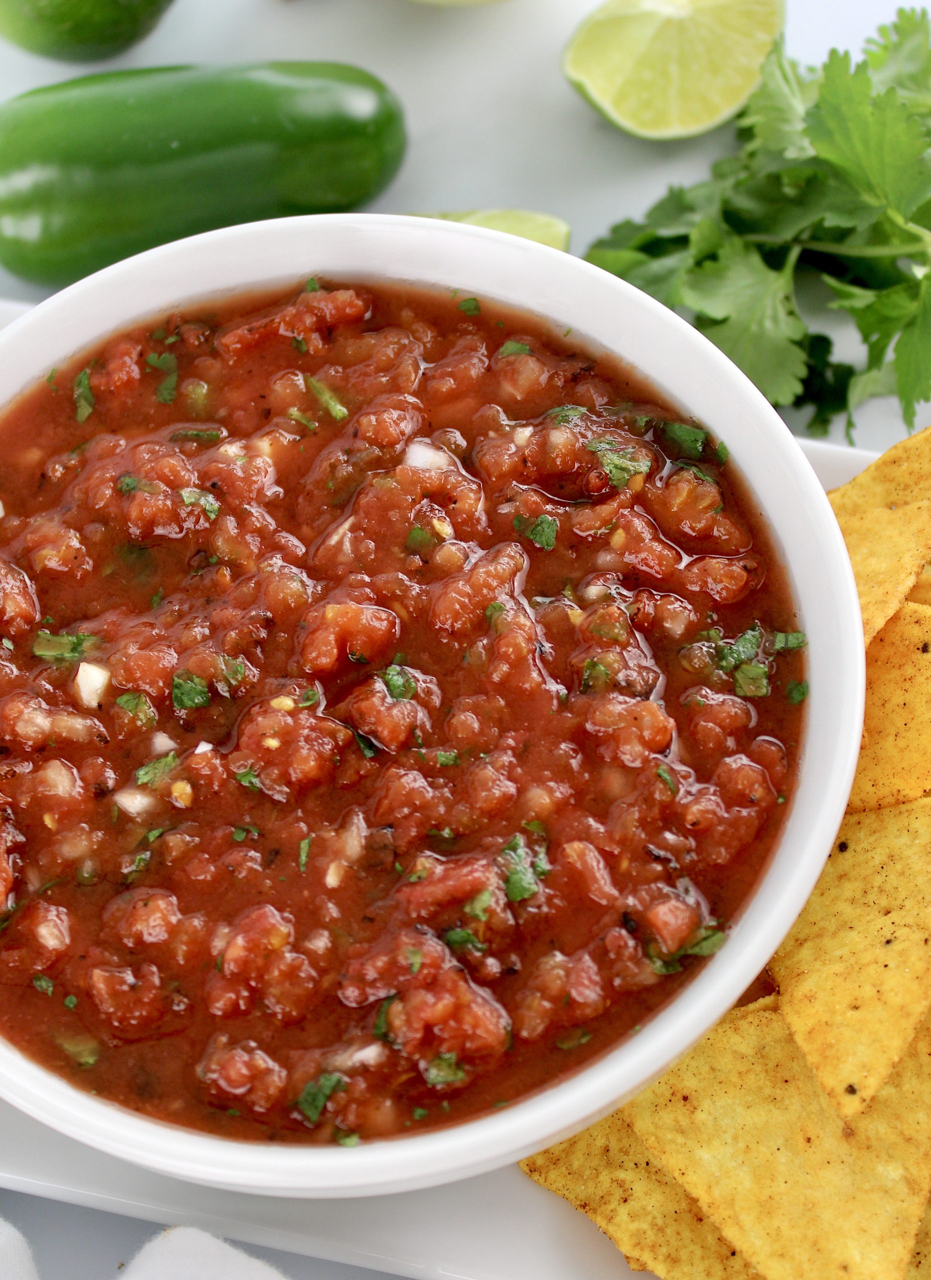 salsa in white bowl with cilantro and chips on side
