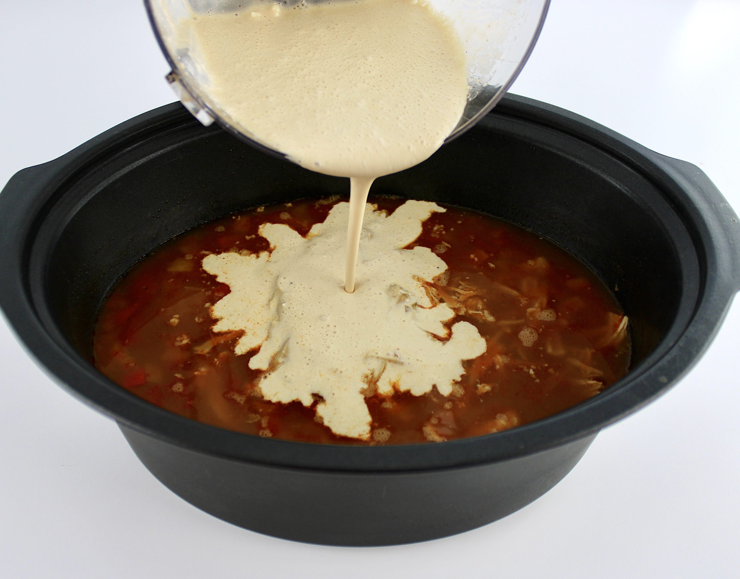 cream cheese mixture being poured from bowl into slow cooker with Slow Cooker Chicken Fajita Soup