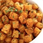 Air Fryer Butternut Squash in white bowl with fresh thyme on top
