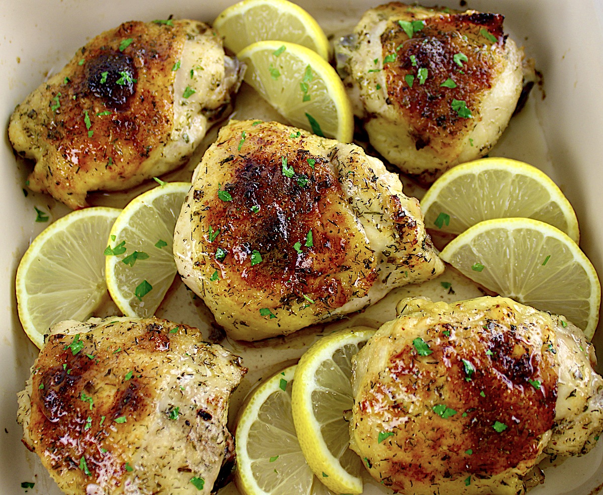 Baked Chicken Thighs in baking dish with chopped parsley and lemon slices