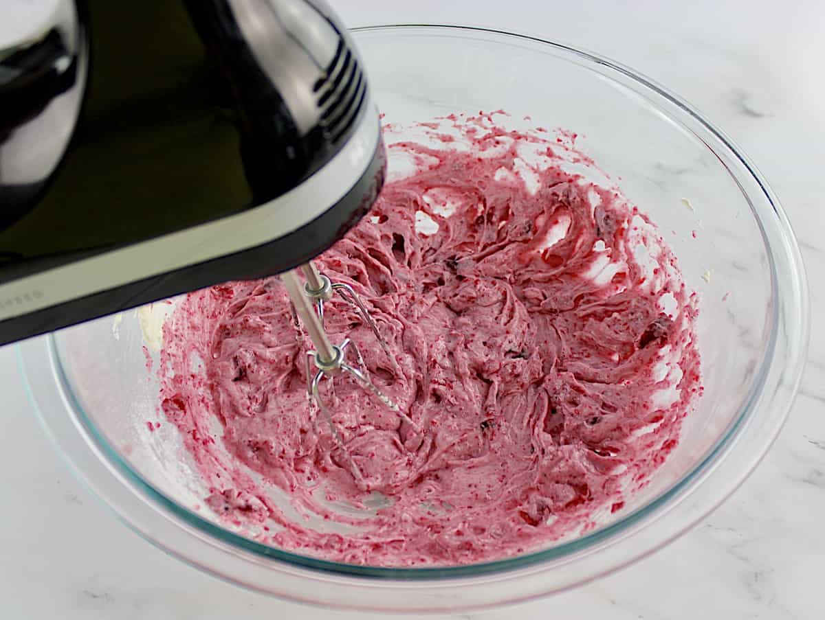 Cranberry Cheesecake Fluff being mixed with hand mixer in glass bowl