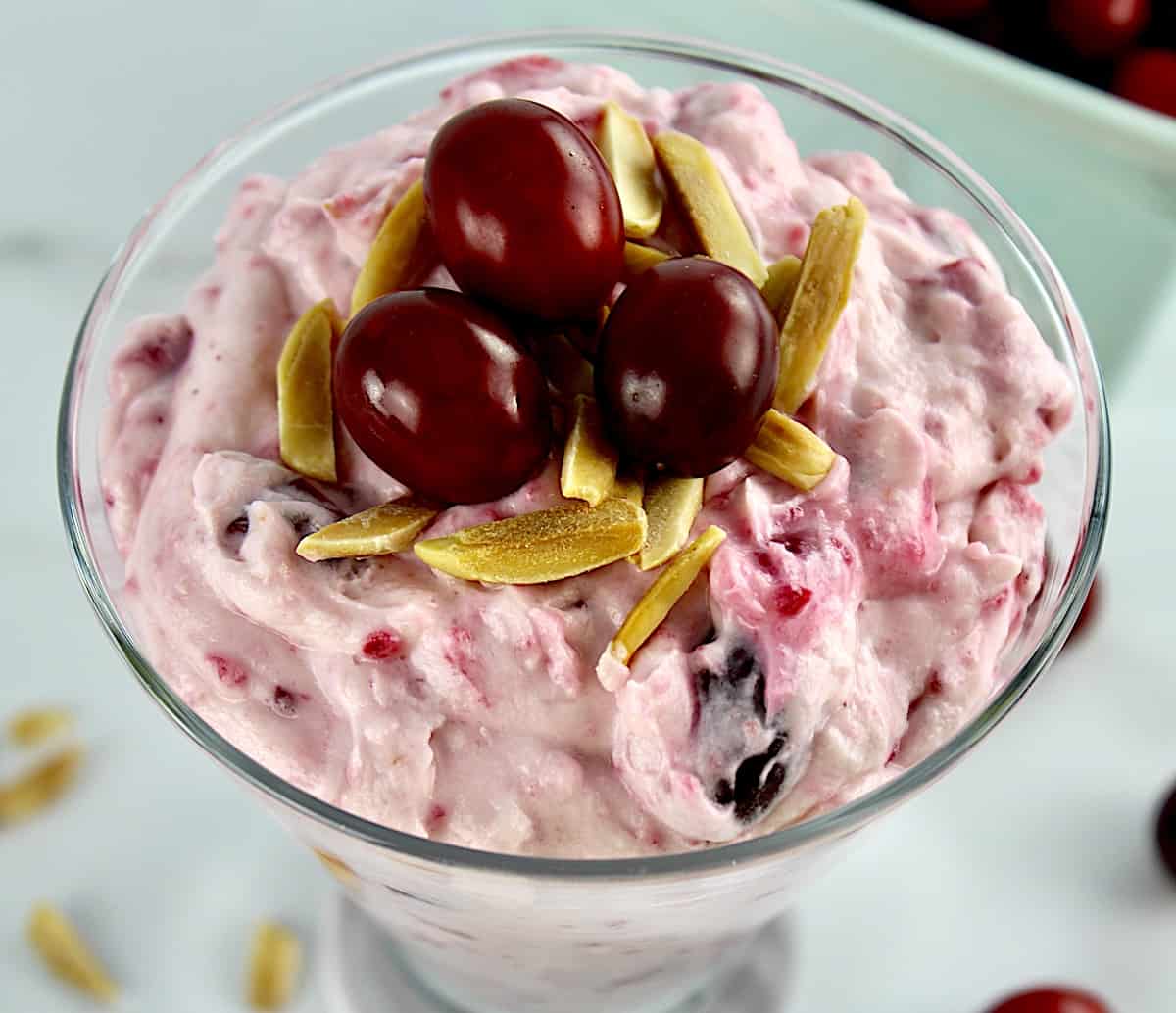 overhead view of Cranberry Cheesecake Fluff inn glass with slivered almonds and 3 cranberries