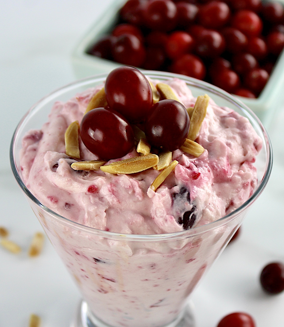 overhead view of Cranberry Cheesecake Fluff inn glass with slivered almonds and 3 cranberries