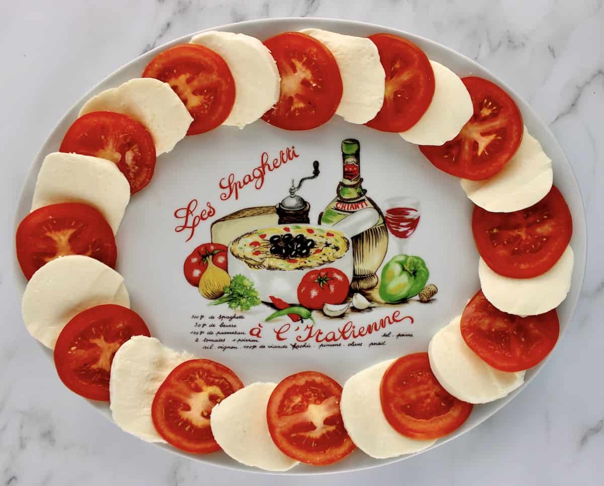 slices of mozzarella cheese and tomatoes around the edge of a platter
