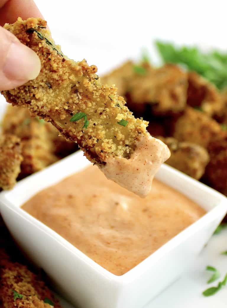Air Fryer Zucchini Frie being dipped into dipping sauce in white bowl