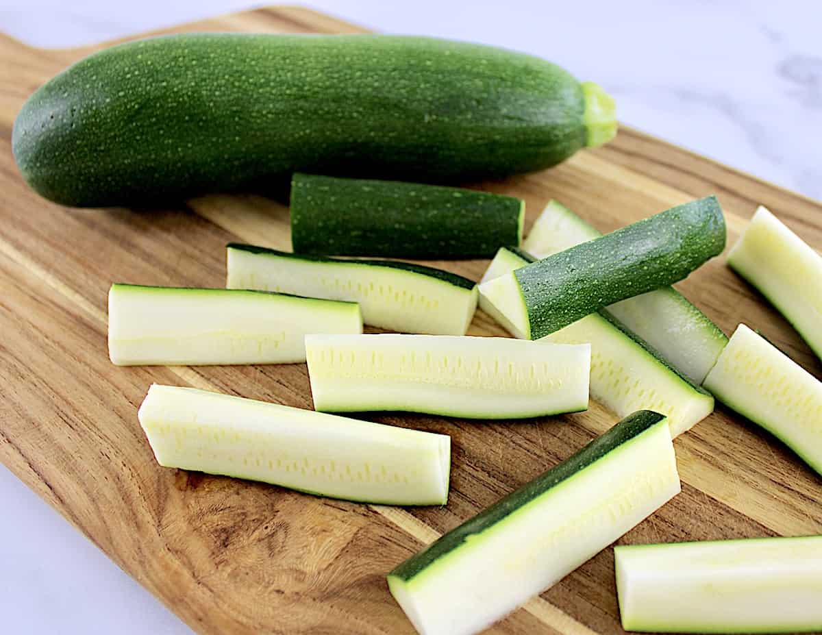 zucchini being cut into fries on cutting board