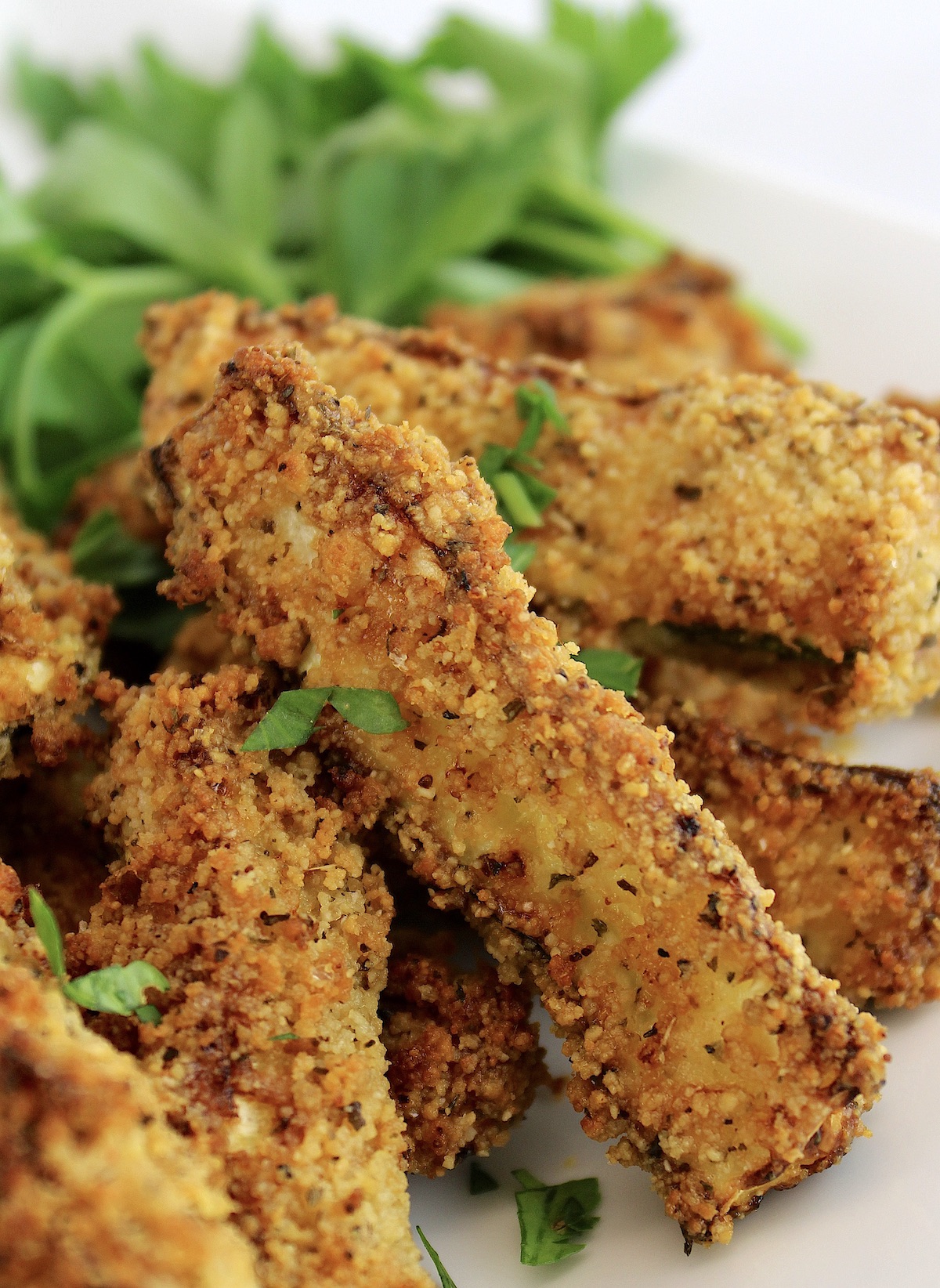 closeup of Air Fryer Zucchini Fries on white plate with parsley