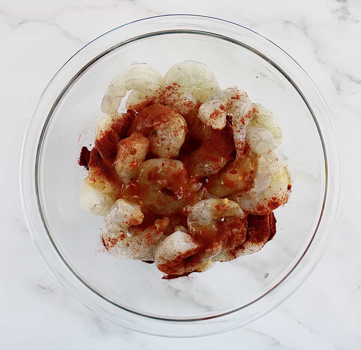 raw shrimp with seasonings in glass bowl