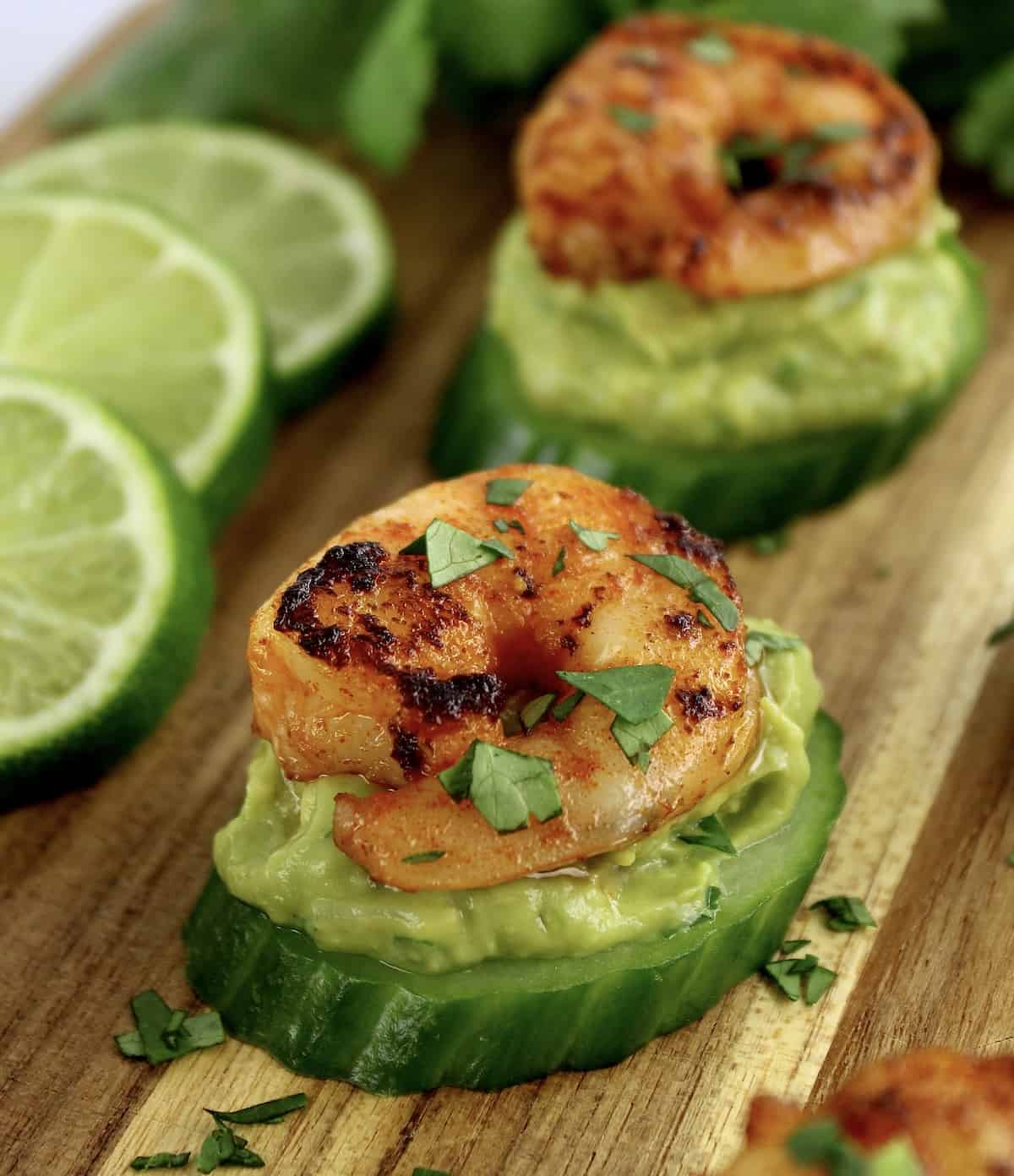 seasoned shrimp on guacamole and cucumber slice on cutting board