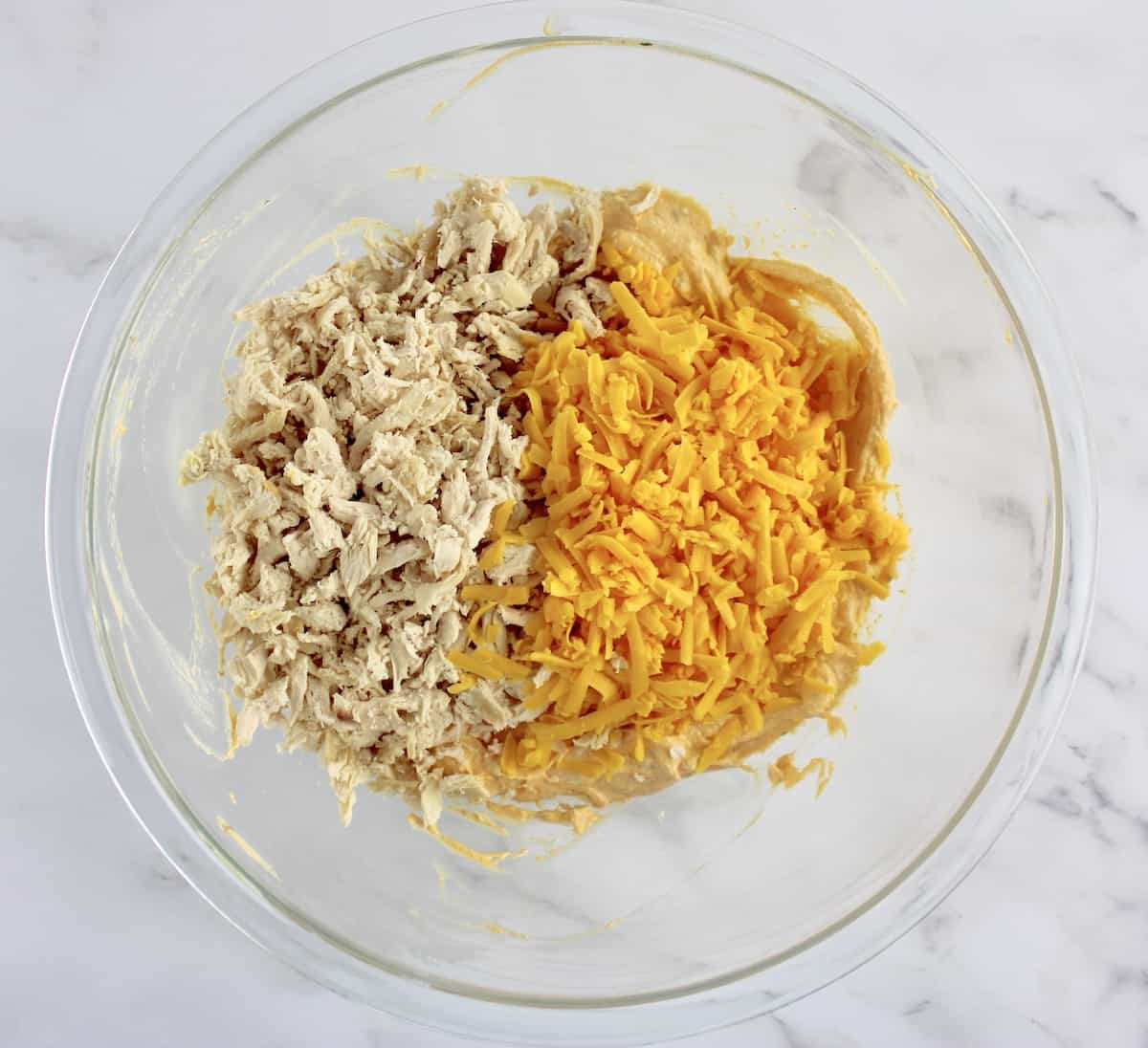shredded chicken and cheddar cheese in glass bowl