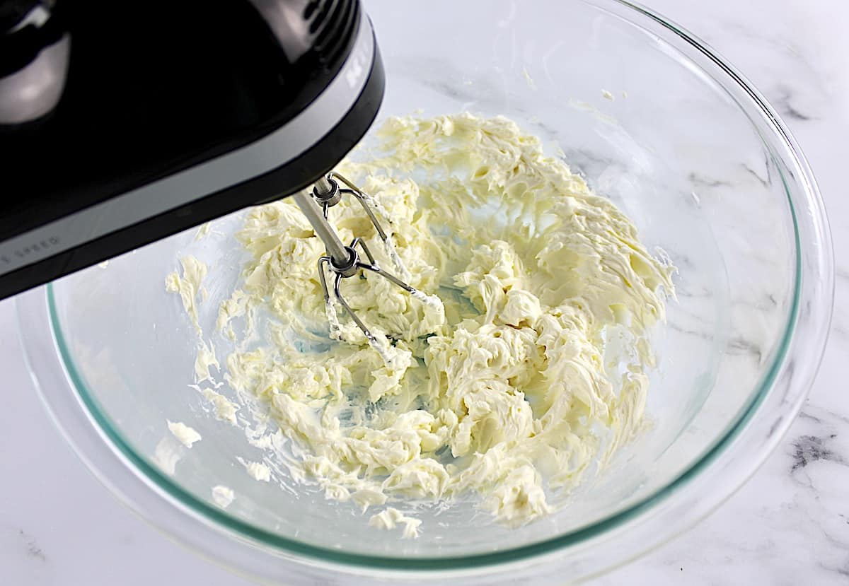 cream cheese being mixed with hand mixer