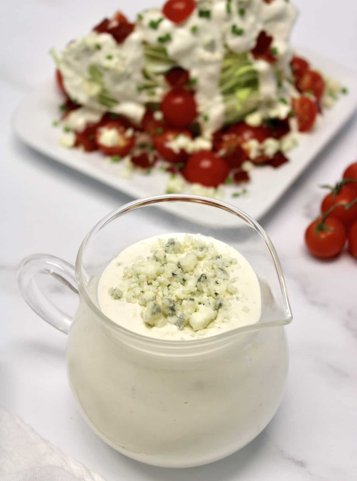 closeup of blue cheese dressing with wedge salad in background