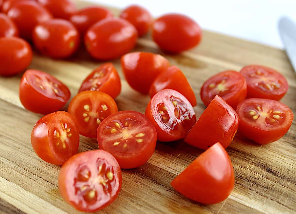 cherry tomatoes cut in half on cutting board
