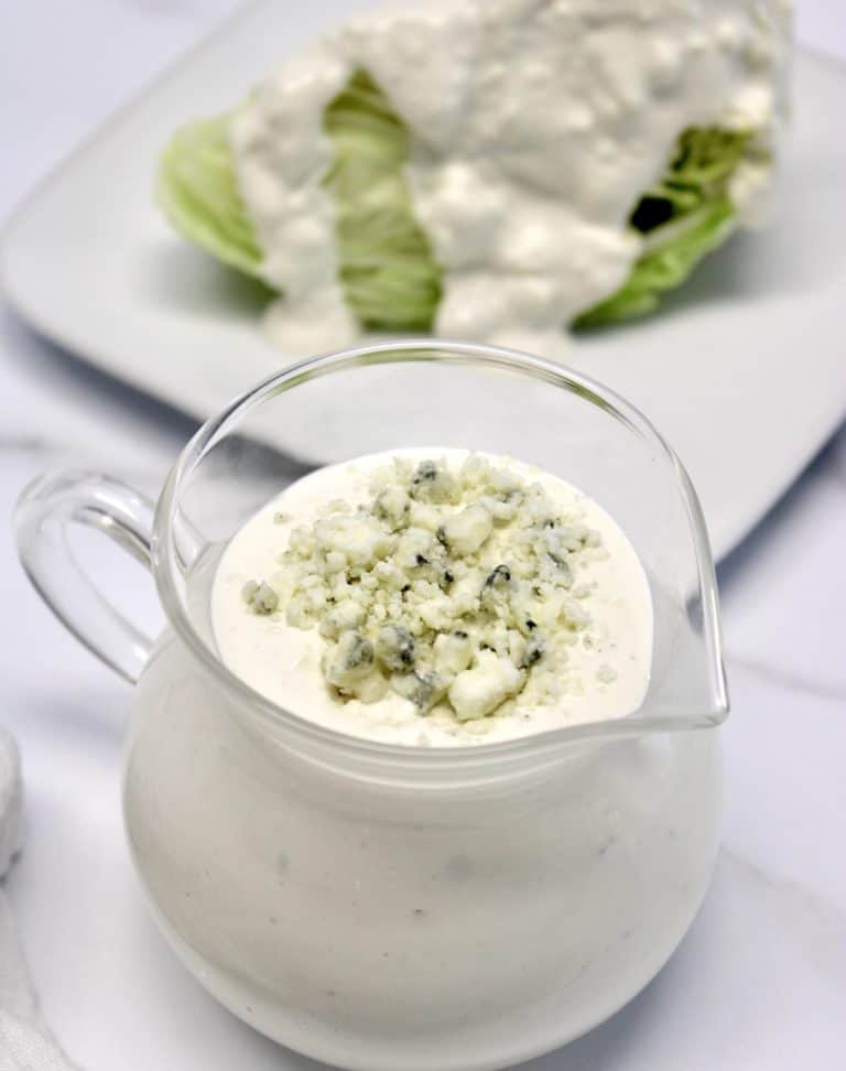 Keto Blue Cheese Dressing in glass pitcher with lettuce wedge in background