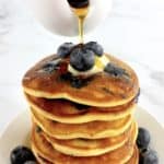 stack of Keto Blueberry Pancakes with blueberries on top and sides with syrup being poured over top