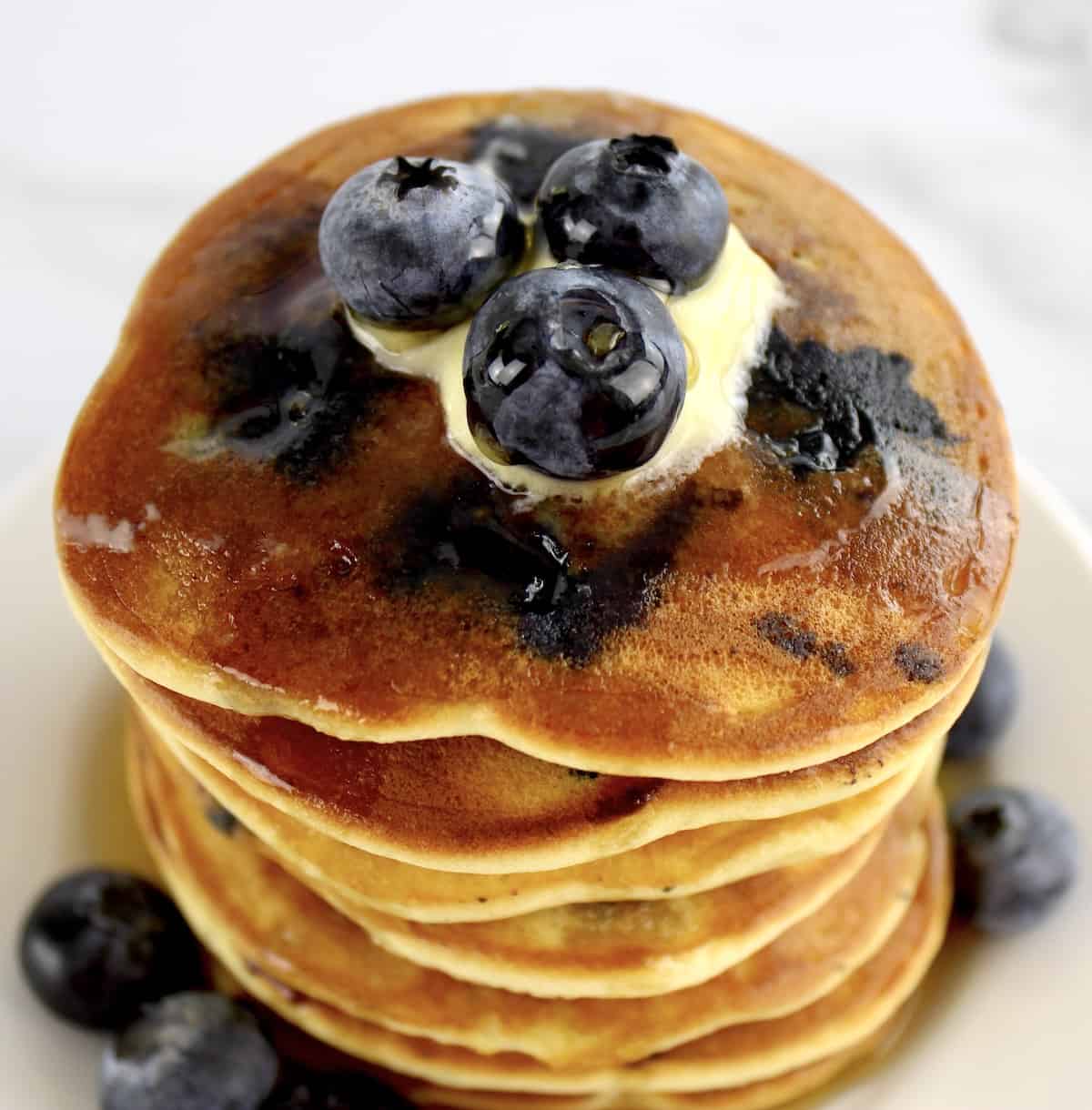 overhead view of stack of Keto Blueberry Pancakes with butter and blueberries on top