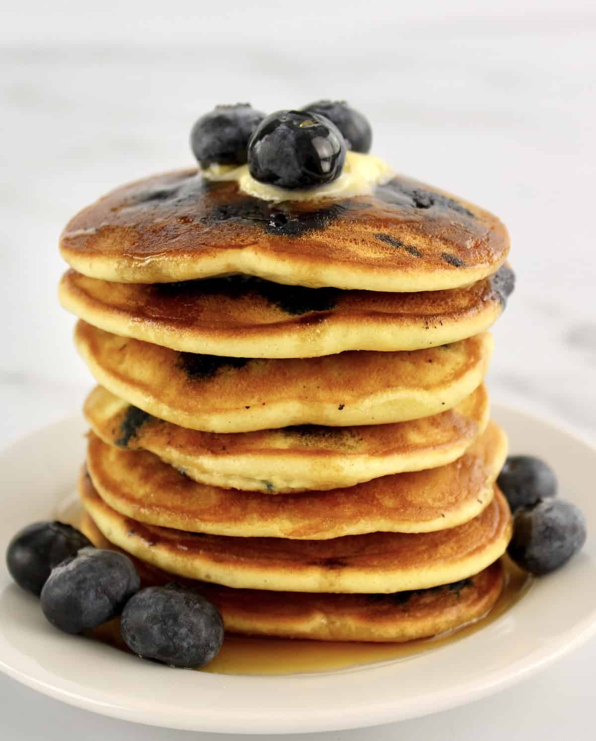 stack of Keto Blueberry Pancakes on white plate with blueberries on top and on sides