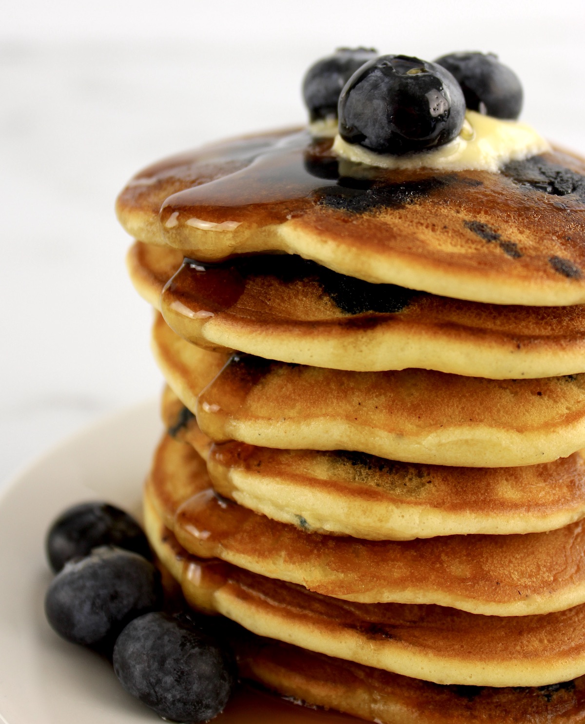 stack of Keto Blueberry Pancakes with syrup dripping down the left side