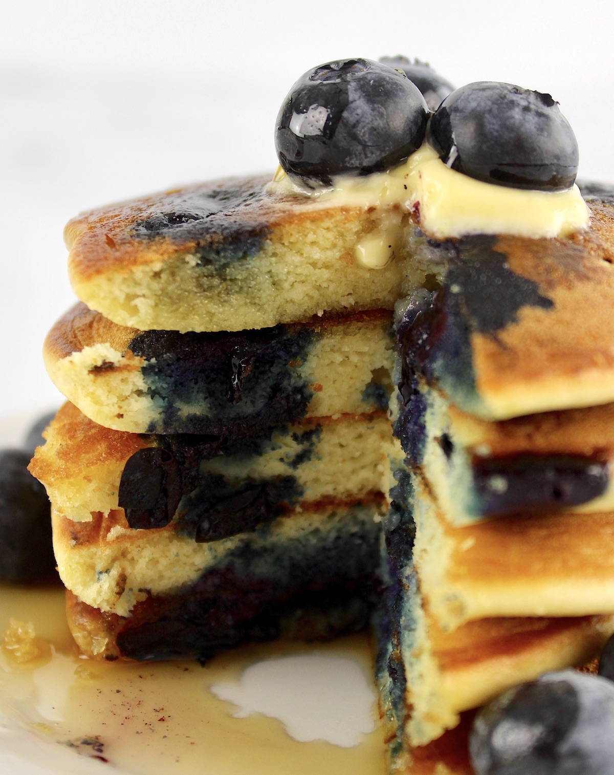 stack of Keto Blueberry Pancakes cut open with blueberries on top