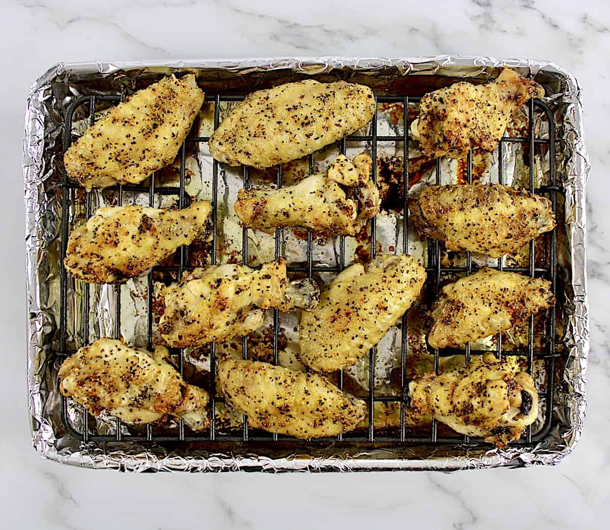 lemon pepper chicken wings on wire rack lined with foil