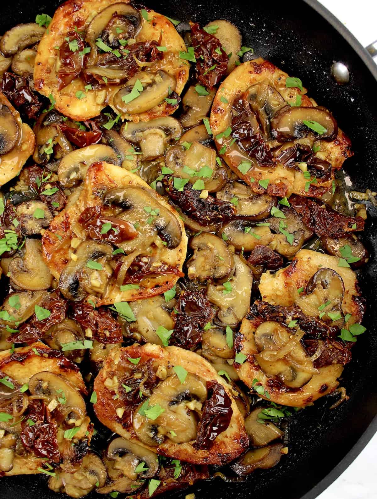 Mushroom Chicken with Sun-Dried Tomatoes in skillet with chopped parsley