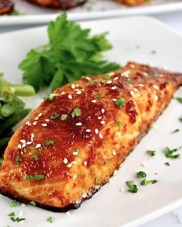 closeup of Asian Glazed Salmon on white plate with parsley in background