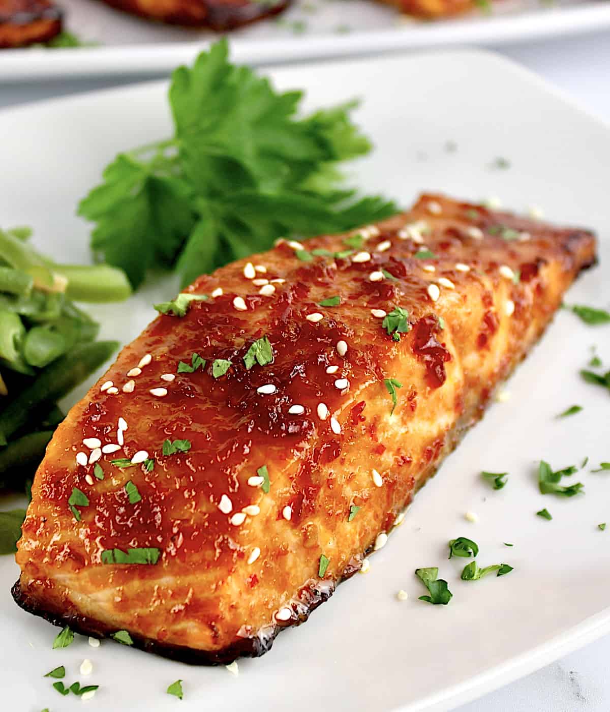 closeup of Asian Glazed Salmon on white plate with parsley in background