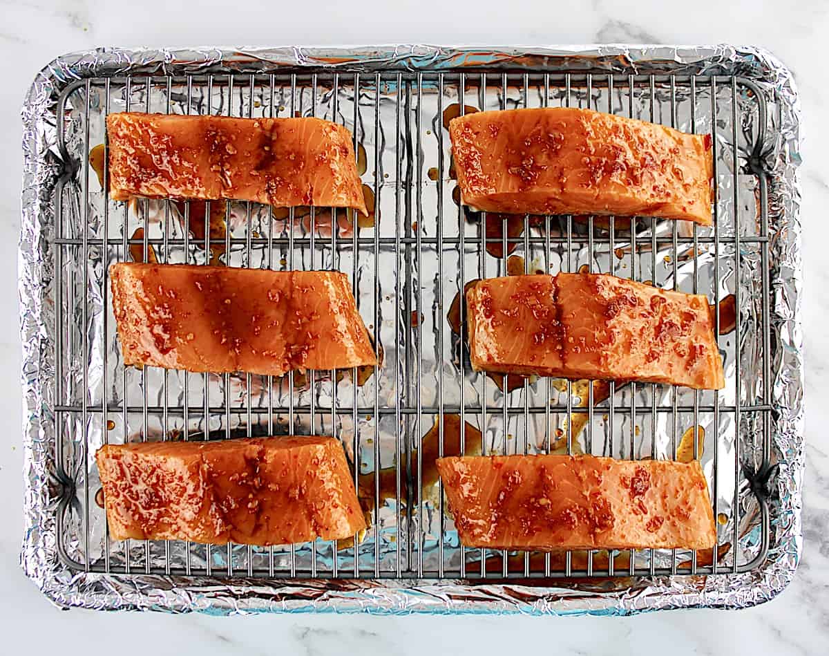 6 pieces of salmon with Asian glaze over the tops on wire rack on baking sheet