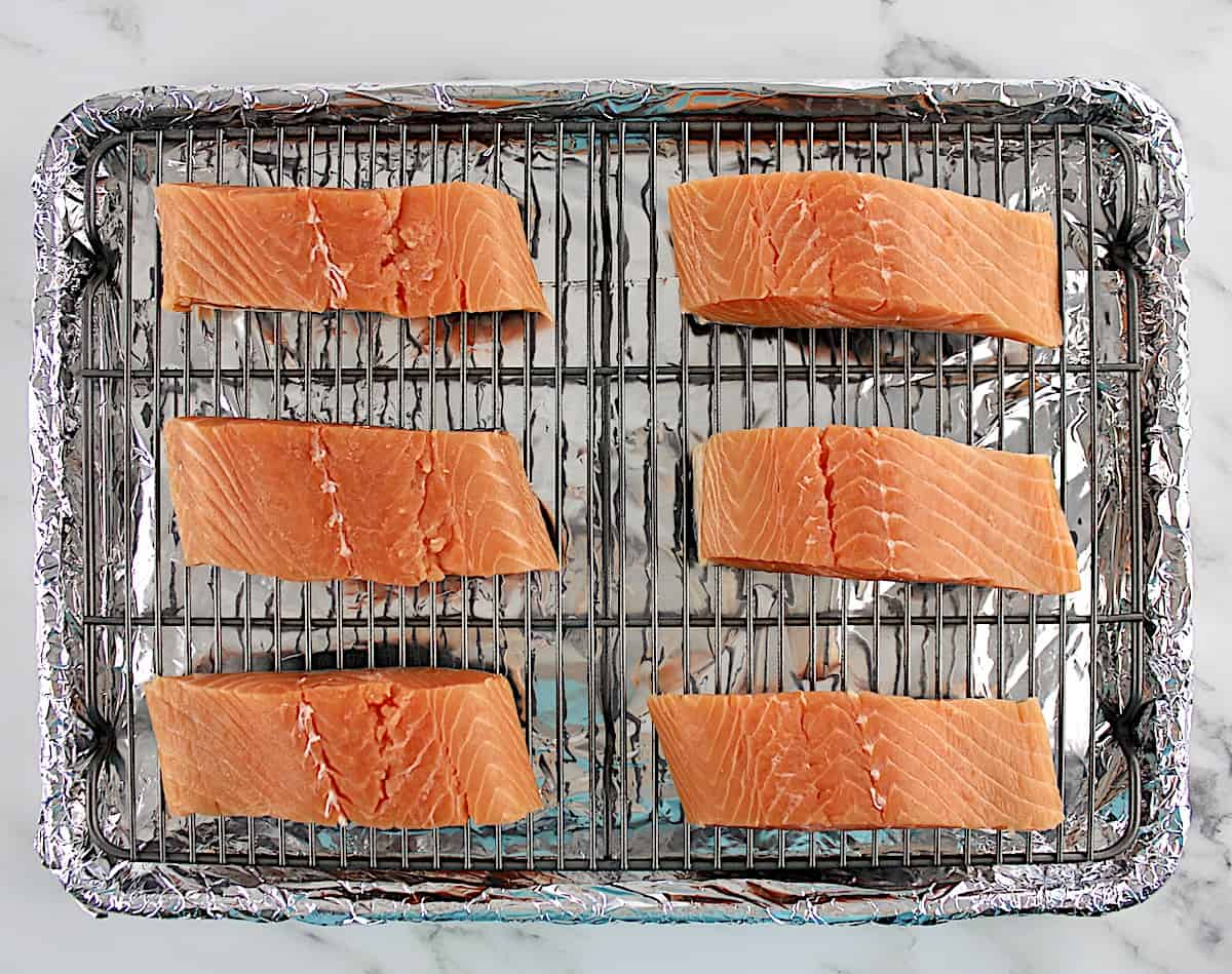 6 pieces of raw salmon on baking sheet lined with a wire rack