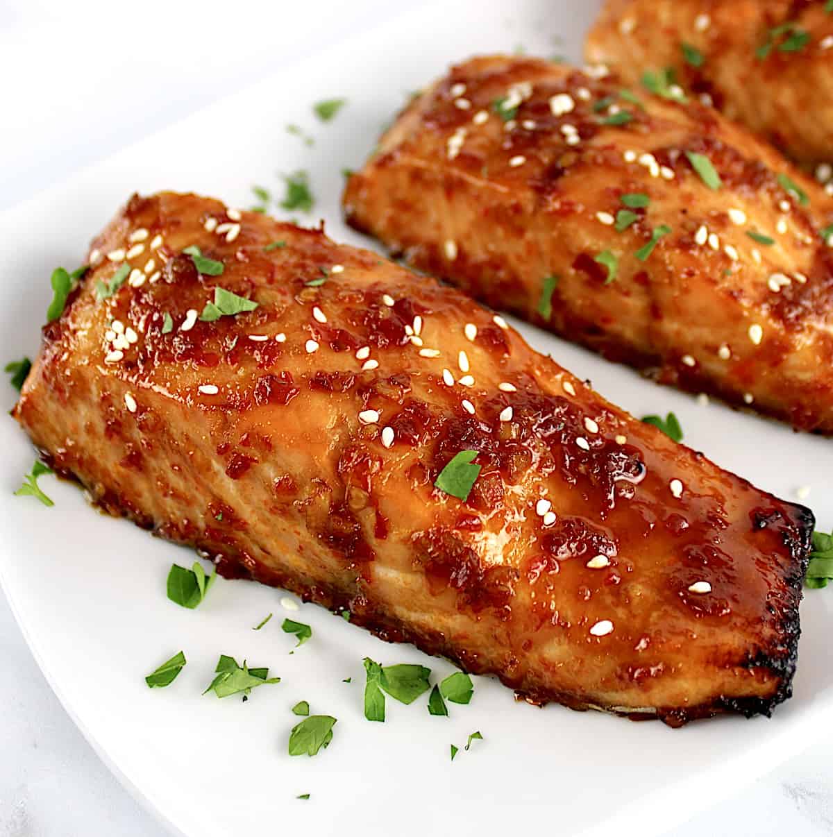 closeup of Asian Glazed Salmon on white plate with chopped parsley