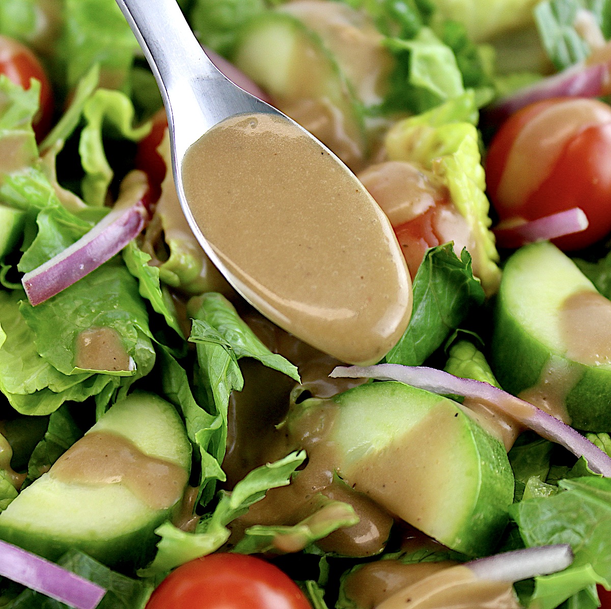 Creamy Balsamic Dressing being spooned over salad