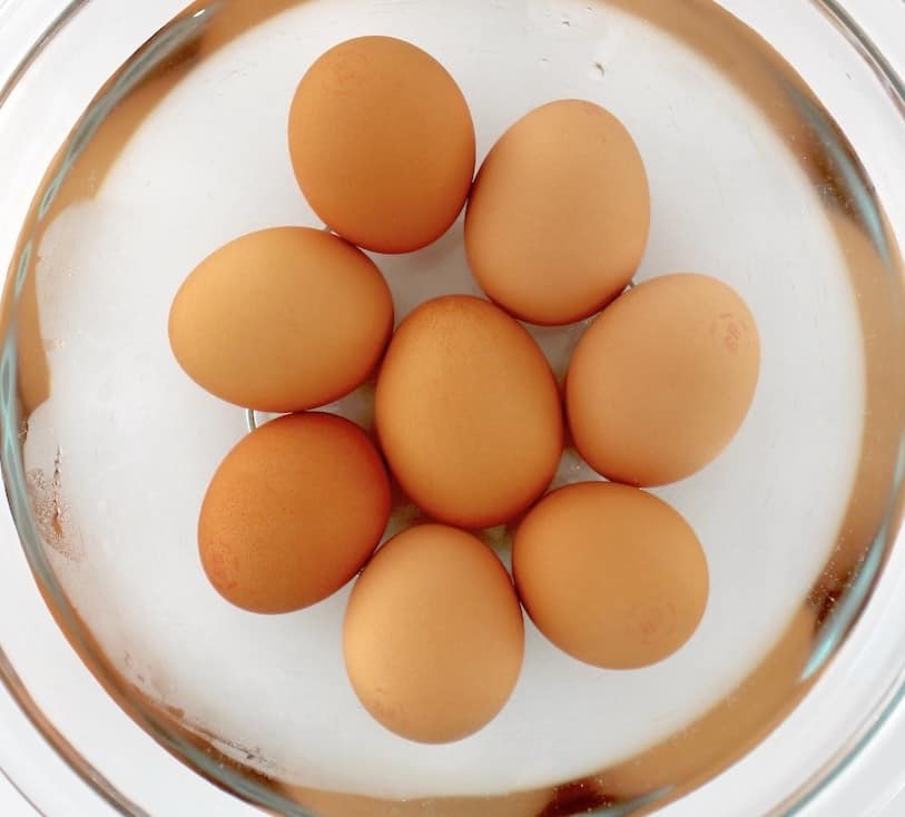 8 brown eggs in glass bowl with water